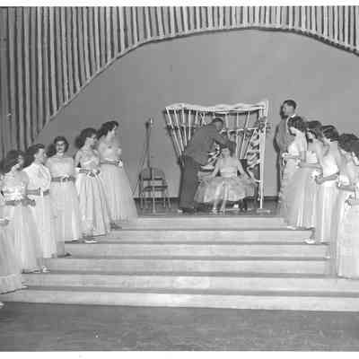 Emcee places crown upon head of pagent queen in front of her court of pagent princesses