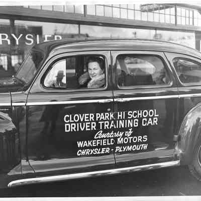 Iva Alice Mann wearing fur wrap and sitting in the front seat of a Clover Park Hi School Driver Trianing Car