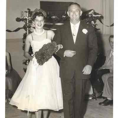 Rita Gardener in flower crown with bouquet arm in arm with Tommy Madden