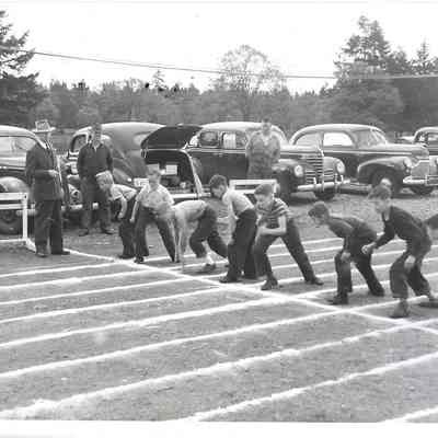 Children at track starting line in front of row of cars