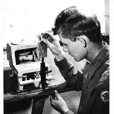 Military member with steaming knife blade pointed into table