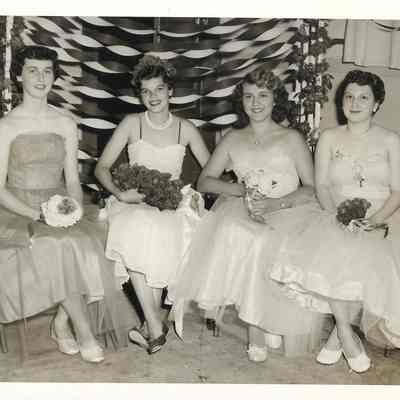 Verene B, crowned Queen Rita Gardener, Gail Baker, and Esther Cedergren sitting with boquets in front of streamer stand