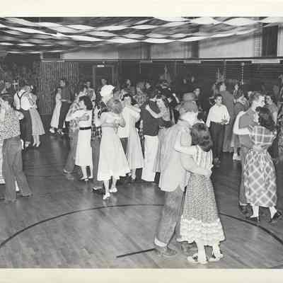 Teenagers dance in a gymnasium that has been decorated