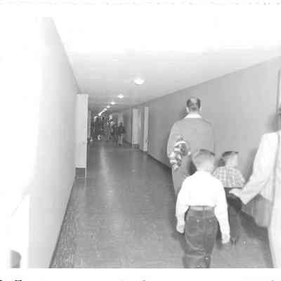 Adults and children in partially empty hallway