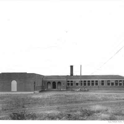 Side of Lakeview School with cloudy sky and several bicycles leaning against a telephone post