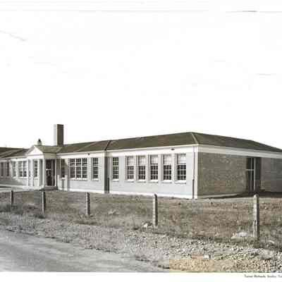 3/4 view of Lakeview School with overcast sky and several posts running along paved road