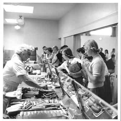 Teenagers getting lunch from lunch ladies in Hudtloff Junior High School cafeteria 1953