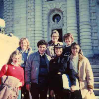 Photograph of Rita Barchetti, Leslie Murray, Janette, Nelson Hincatie, Susan Gibb, Carmen Graciela Melgarejo, Joanne Mason and in front of Bancroft Hall in Annapolis, Jan 1984