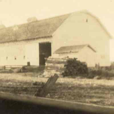 The Big Barn built by Ben Peterson 1935-36: A photograph of a large light-colored at an angle, possibly taken from the road. 2023.001.I.E.a.1