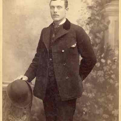 Photo portrait of a young man in a suit standing, holding a hat in his right hand, his left hand behind his back. Reverse side says "W.I. Williams & Co. Photographers at 914 Market Street in Baldwin Hotel Block, San Francisco, CA": 2024.III.I.3.b.002