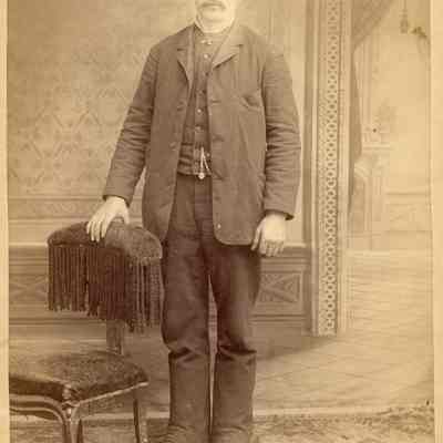 Photo portrait of a white man in a suit and hat standing in a nicely arranged photo set. Photo taken by Worthington, location unknown.: 2024.III.I.3.b.003