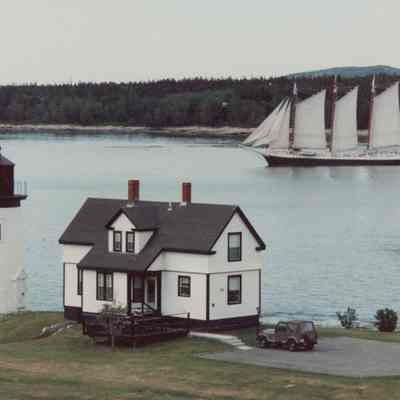 Prospect Harbor Lighthouse and Keeper's Cottage with Victory Chimes Schooner in the background.