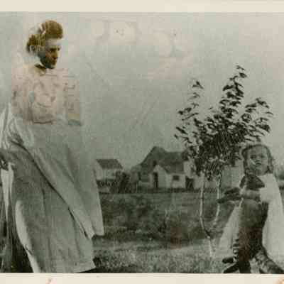 Nellie and Avis Temple playing with a cat on the homestead.