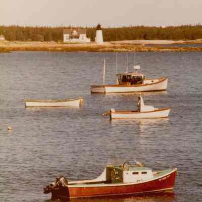 Prospect Harbor Lighthouse and Keeper's Cottage with lobster boats in the foreground.