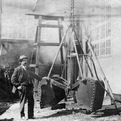 James E. Merrill with machine equipment, early 1900s