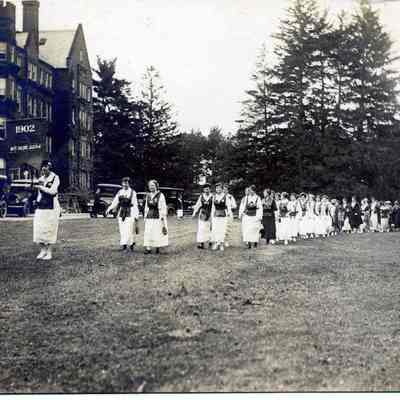 Vassar graduation,  graduates march past buildings behind "1902" banner