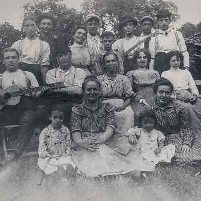 Group photo of the Retaliate family outdoors, some holding musical instruments.