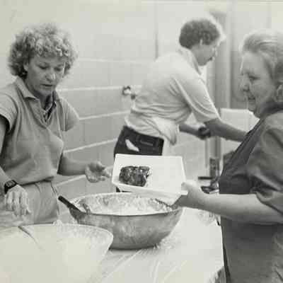 Marie Ed Omsberg serves potato salad to Barbara Neumann