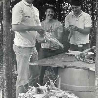 Ralph Kuchar, Dave Sinnaeve, and Gerard Turano husk corn for the barbecue dinner