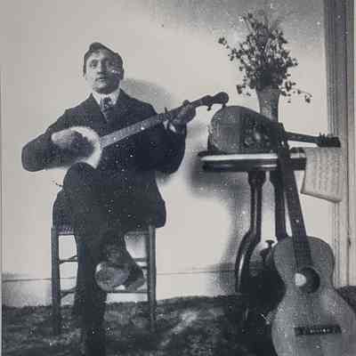 Man of Retaliate family sitting down playing a string instrument.