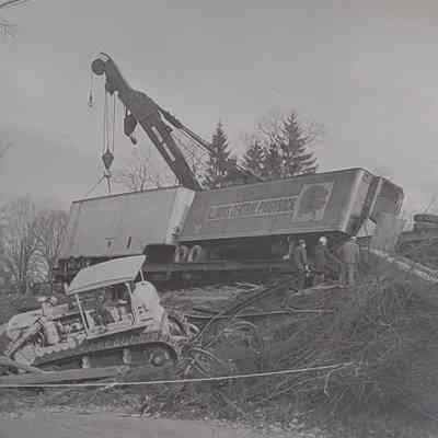 A crane lifts a derailed Illinois Central boxcar.
