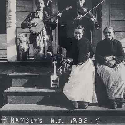 Group of 4 people from the Retaliate family and a dog sitting on the front porch of their house.