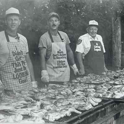 Behind a "smoke screen" John Krawczyk, Dave Marstein, and Andy Rozanski roast barbecued chicken pieces