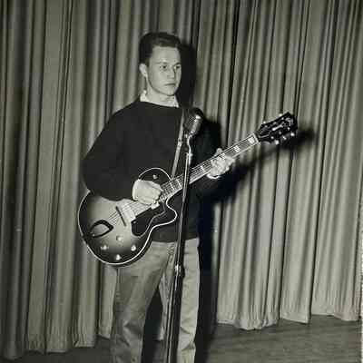 A photograph of Morris playing his guitar.