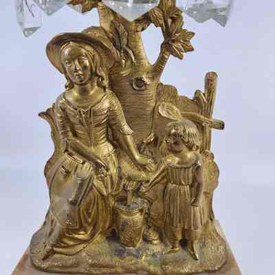 Brass depiction of woman and child outside getting water