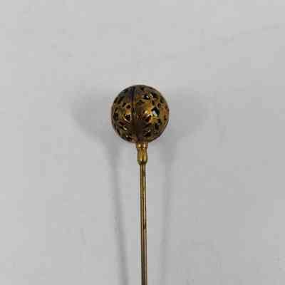 Golden colored pinhead with geometric pattern carved out