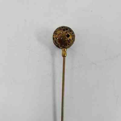 Golden colored pinhead with geometric pattern carved out