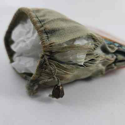 Seam of drawstring purse where fabric has unraveled