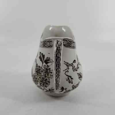 Handle of white pitcher with brown floral design