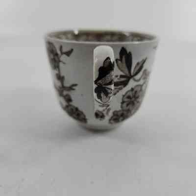Handle with white teacup with brown floral design