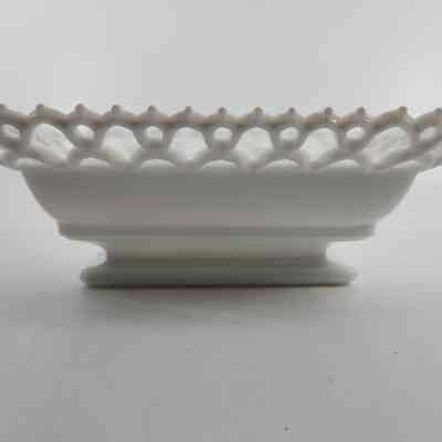 Side of white milk glass box with lace pattern around rim