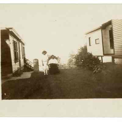 Woman and girl in yard between houses