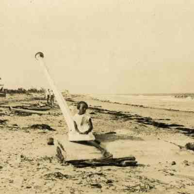little girl sitting on the base of a light pole that has been uprooted by the Sept/ 18, 1926 Hurricane