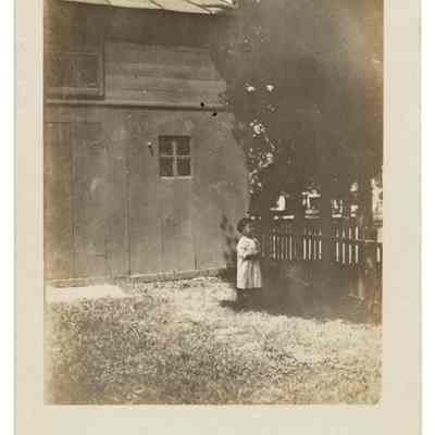 Child in yard by picket fence