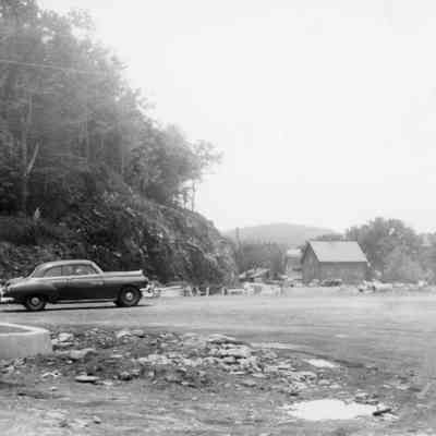 2024.14.8: Barn and Amoco station have been removed; house is still on hill. Written on the back: "Starting the curbings for the new sidewalk."