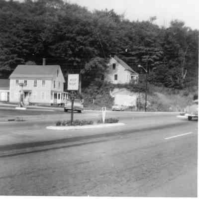 2024.14.11: Corner of Northfield Street and Berlin Street. Barn and Amoco station have been removed; house is still on hill. Written on the back: "The good old corner. Believe it or not those are petunias in the islands."