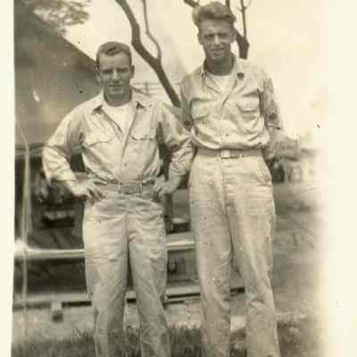 Photo of two men standing outside tent during WWII.