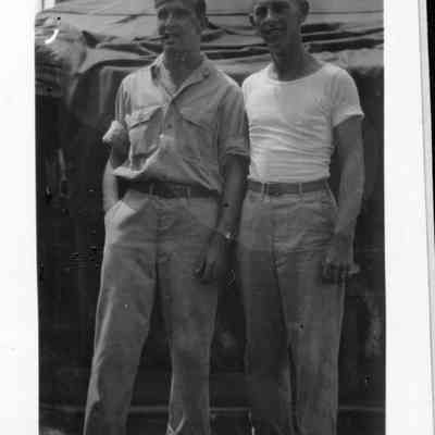 Photo of two men standing outside tent during WWII.