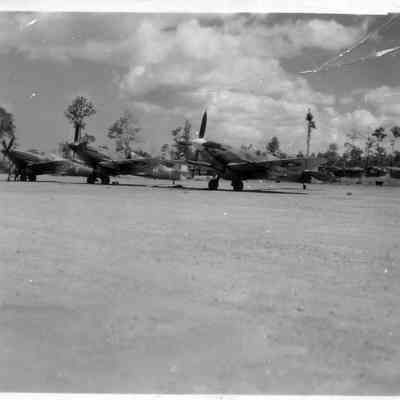 WWII airplanes lined up at airport.