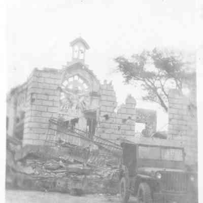 Appears to be a wrecked church with jeep in front.