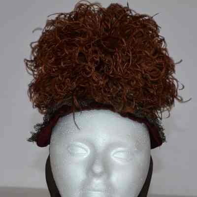 Small bonnet covered in woven ribbons, puff of feathers on front crown and ties