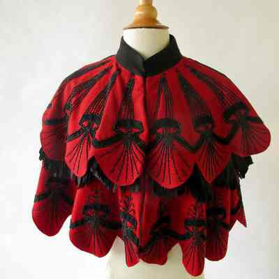 Red scalloped tiered capelet with black beaded and appliqué embellishment and pleated silk