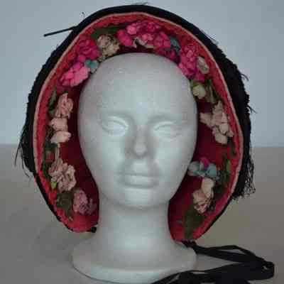 Velvet bonnet with feather on brim and faux flowers on interior brim, ties