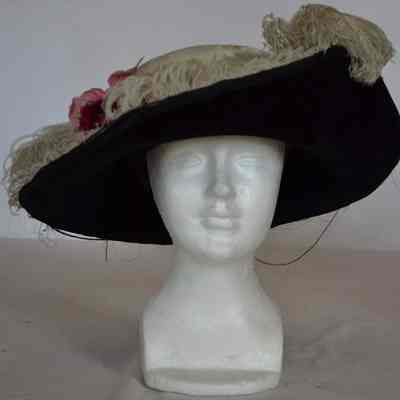 Wide turned up brim hat with feather and flower embellishment