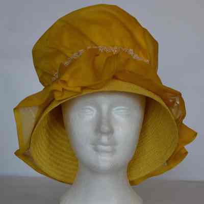 Straw hat with down turned brim and large fabric ruffle covering brim and crown