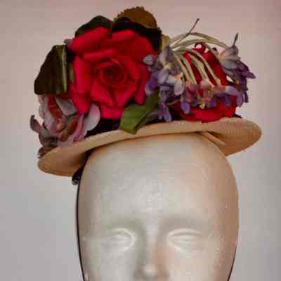 Small straw boater hat with purple velvet ribbon and multiple faux flowers embellishment